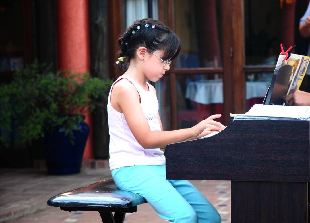 Foto mía tocando el piano en un recital cuando era pequeña